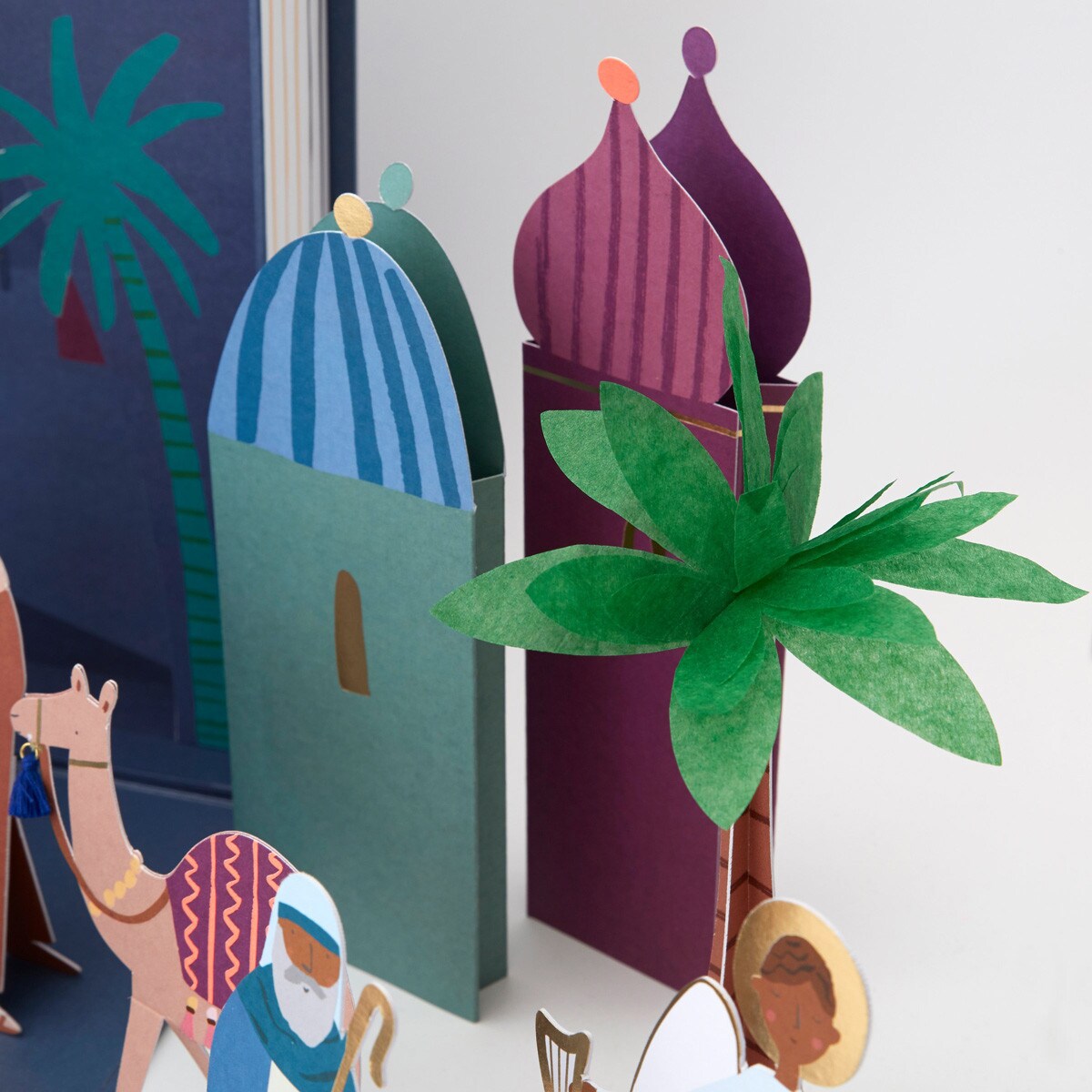 Colorful paper models of a mosque and palm trees on a white background