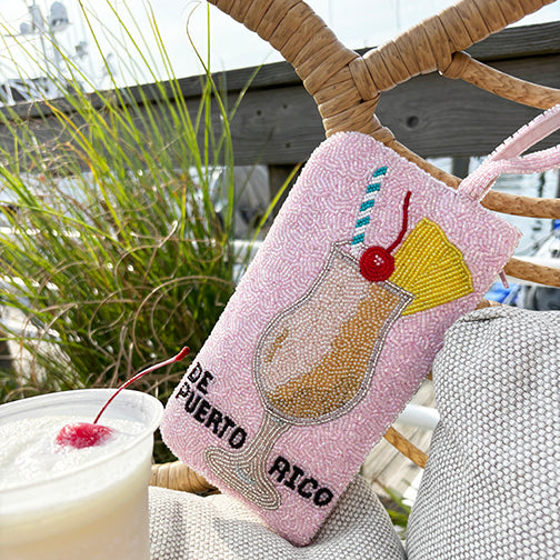 Piña Colada de Puerto Rico pink beaded wristlet purse with cocktail design, handmade Boricua beaded bag next to real piña colada drink