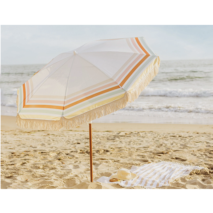 Summerland 6.5 ft portable beach umbrella with cotton fringe and stripe pattern on sandy beach, tropical island style