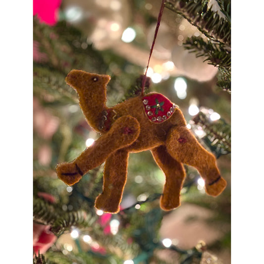 Felt camel ornament hanging on a Christmas tree with blurred lights in the background