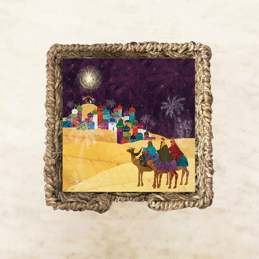 Colorful illustration of the Three Wise Men on camels approaching Bethlehem under a bright star, with vibrant domed buildings and palm trees on festive Christmas-themed paper napkins.

